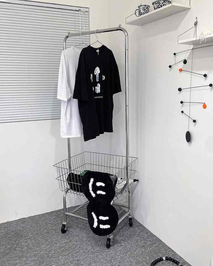 A simple room with white and gray tones featuring a central metal coat rack and a mobile for a clean atmosphere