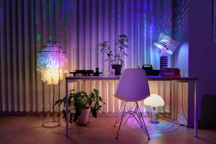 Cozy home office space with CMYK colored lighting spreading ambiance through mood lights and table lamps across workspace