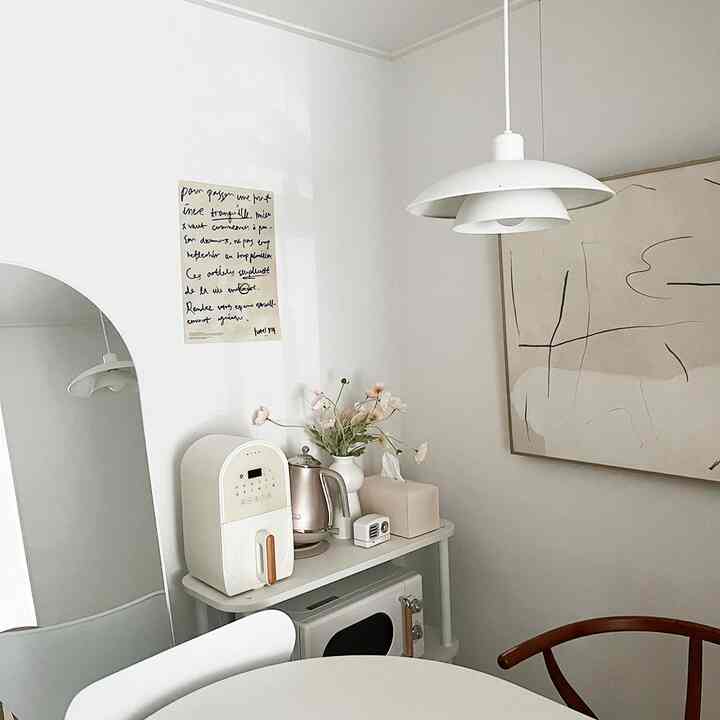 A modern kitchen space in white and wood tones, featuring a compact kitchen cart and dining table with a simple interior design