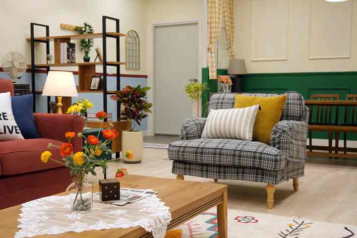 ナチュラルカラーとブラウン調のリビング、チェック柄のアームチェアとコーラル色のソファ、木製コーヒーテーブルが配置されたヴィンテージな雰囲気のインテリア