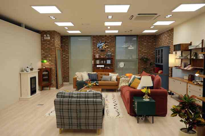 Industrial style living room with red and brown sofas, featuring brick walls and a white fireplace