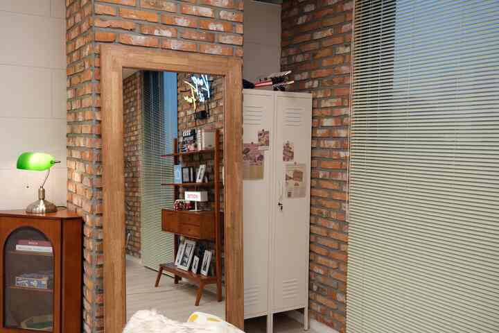 ナチュラルカラーとレンガ壁のリビング、木製の大型全身鏡と金属製キャビネットが配置された雰囲気のあるインダストリアルインテリア