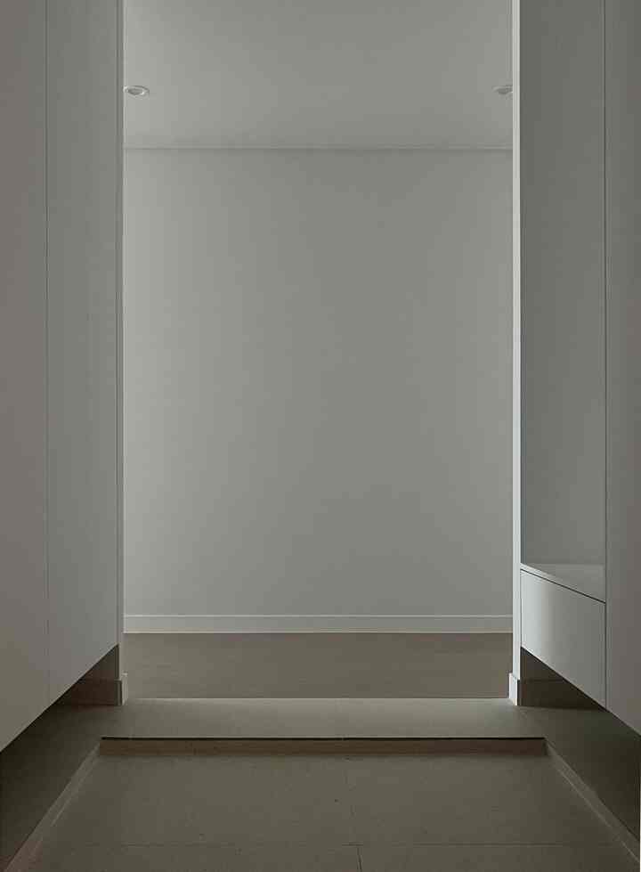 白とベージュのトーンの玄関、左右のシューズラックとタイル床が調和したモダンな空間