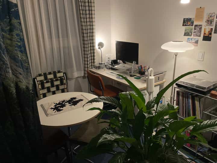 白と茶色のトーンの小さなリビング、丸テーブルとコンパクトなホームオフィスが調和した雰囲気のあるインテリア