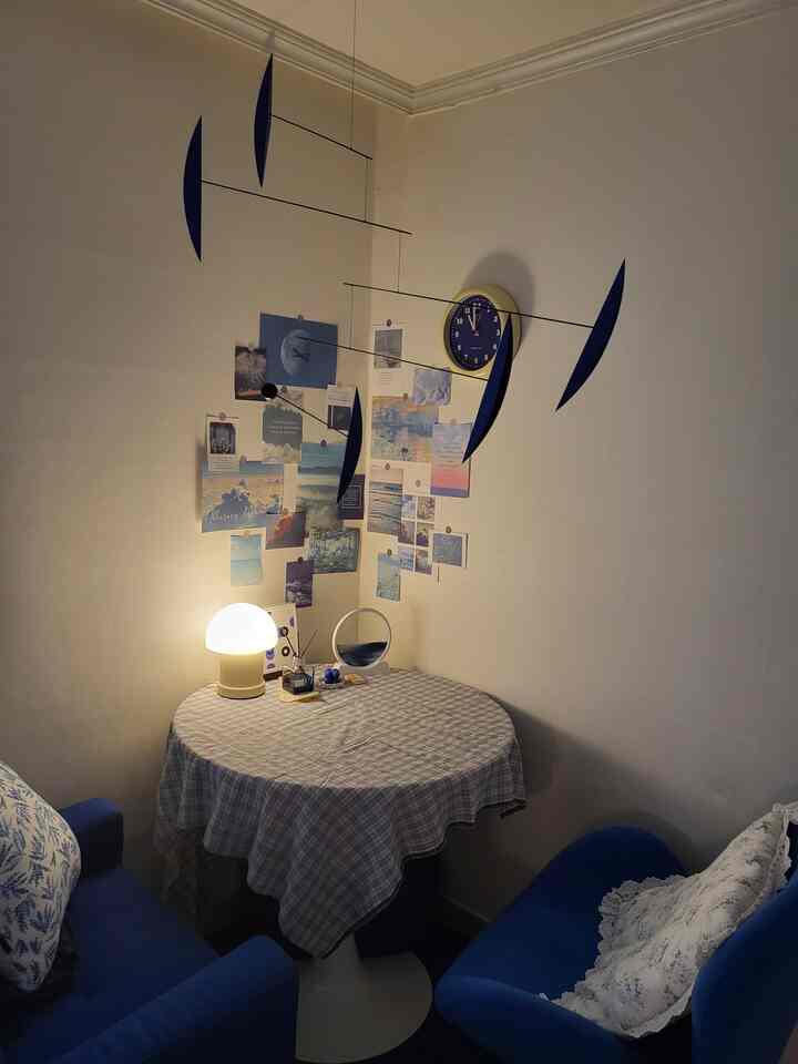 青と白のトーンでまとめられた居心地の良い正方形の部屋、丸テーブルと二つのソファが配置されたおうちカフェスタイルの空間