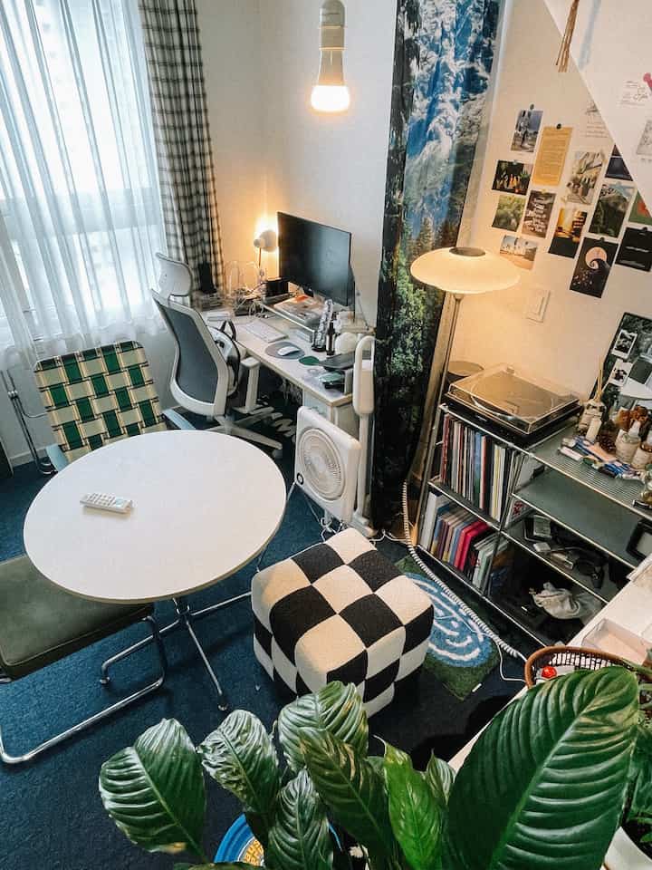 Blue-toned living room featuring a black-and-white checkerboard stool and desk with computer setup