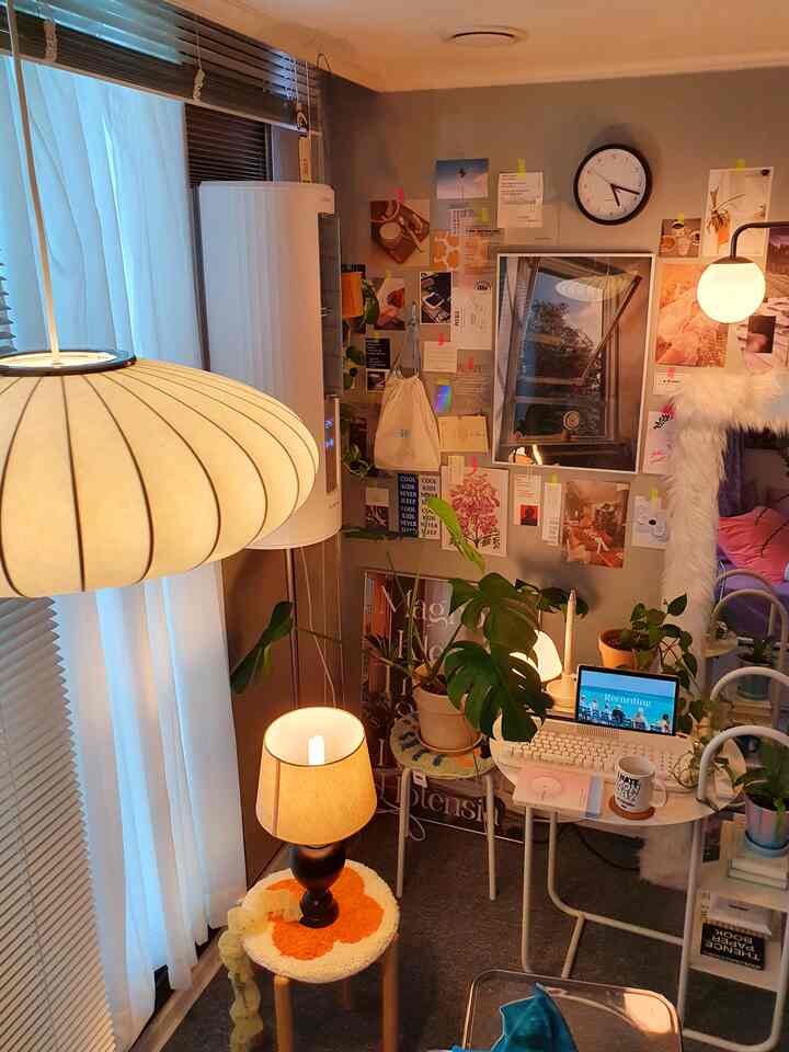 温かみのあるウッドトーンとヴィンテージカラーが調和する狭いリビングのホームオフィス、多様な植物とポスターが配置された雰囲気のあるインテリア