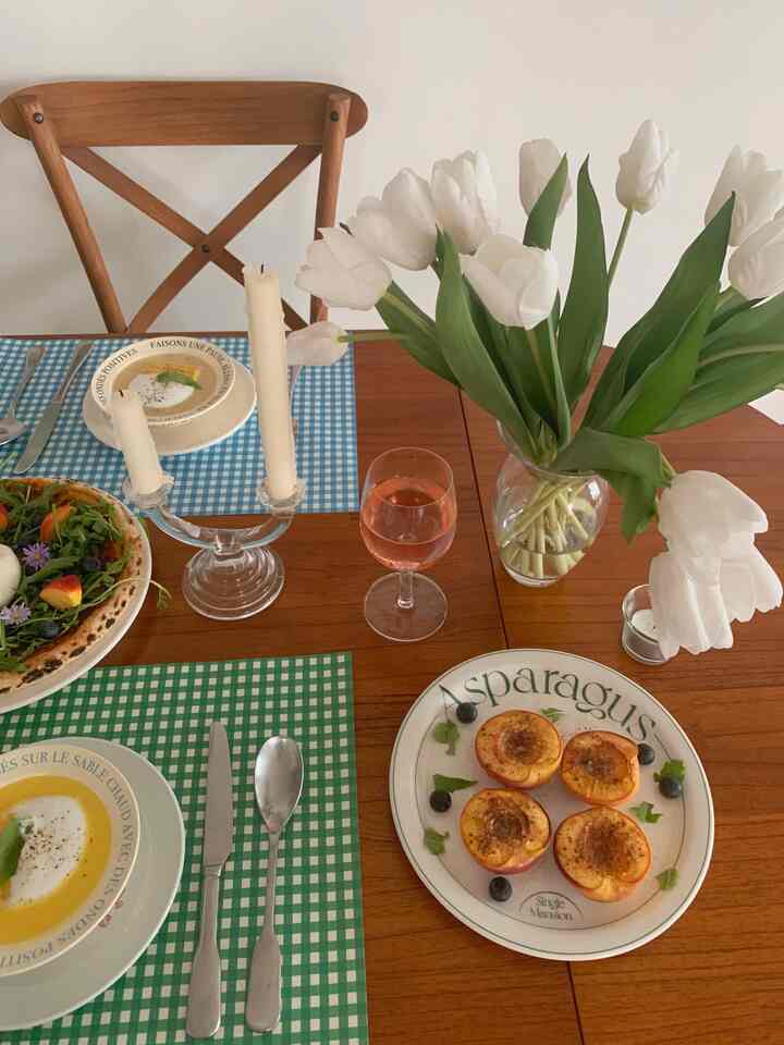 Warm brown wooden dining room featuring a dining table and chair, with white artificial tulips and baked peaches on plates creating cozy home dining atmosphere