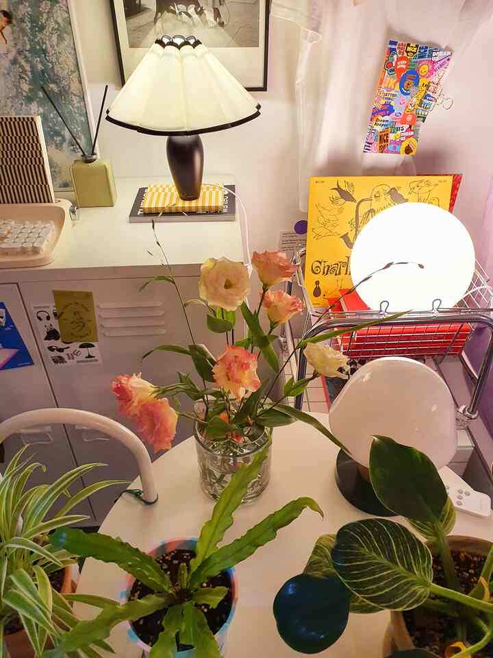 White and brown toned bedroom featuring a central table with flowers and plants, mood lamps creating a warm atmosphere