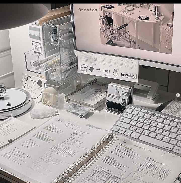 Monotone toned home office featuring a white desk, monitor, and organized storage supplies in a focused study environment
