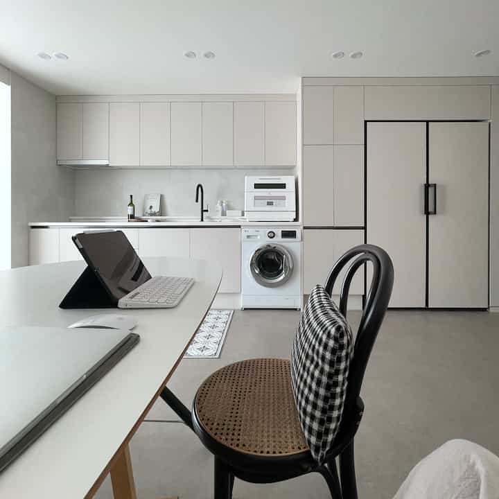 Bright beige-toned modern kitchen featuring built-in appliances and a remote work table in a clean space