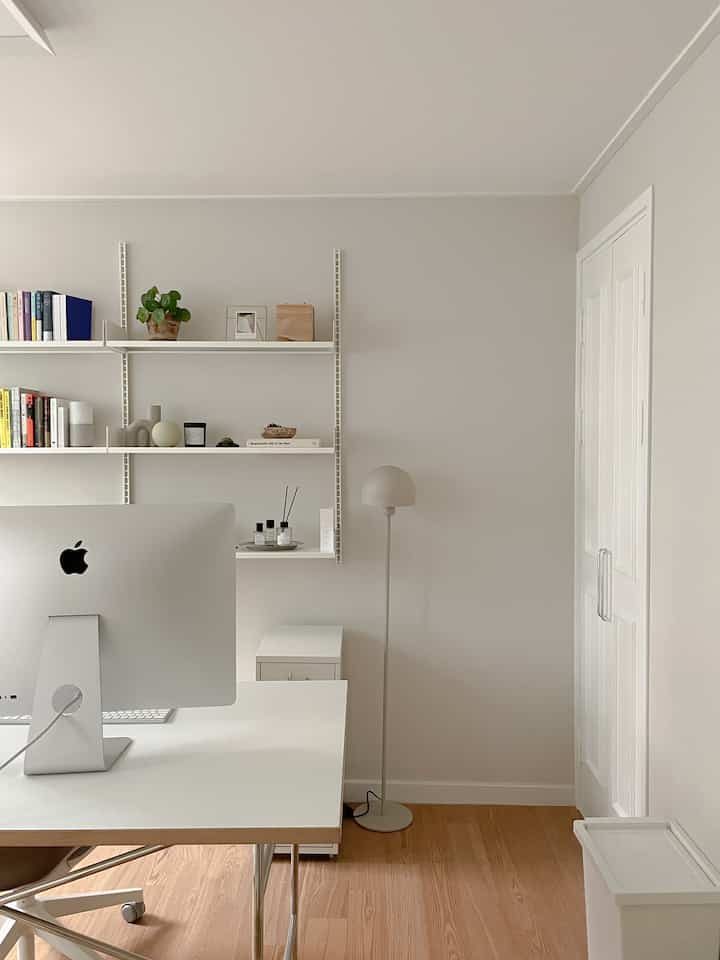 ホワイトトーンとナチュラルカラーの床が特徴的なモダンなホームオフィス、iMacとデスク、フロアランプが配された清潔感のある空間