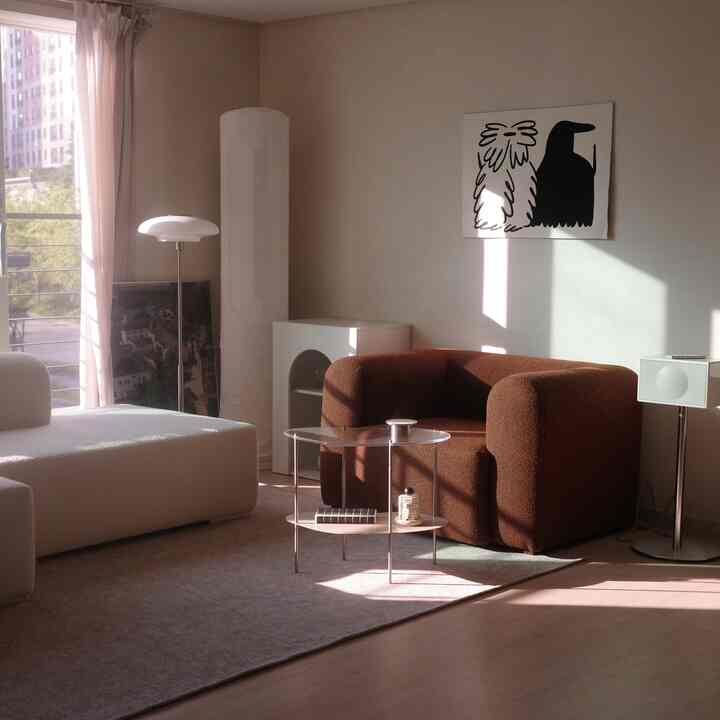 A living room in soft white and brown tones featuring modern sofas, a rug, and a floor lamp creating a cozy atmosphere