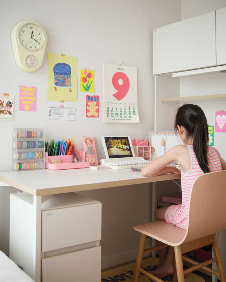 White walls and desk in a kids' study room decorated with pink stationery, creating a cozy and charming atmosphere