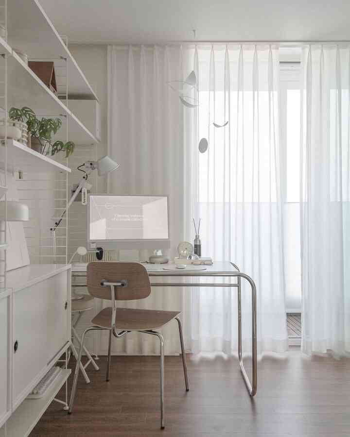 Bright white-toned home office featuring wooden flooring, simple desk and chair with a minimalistic atmosphere