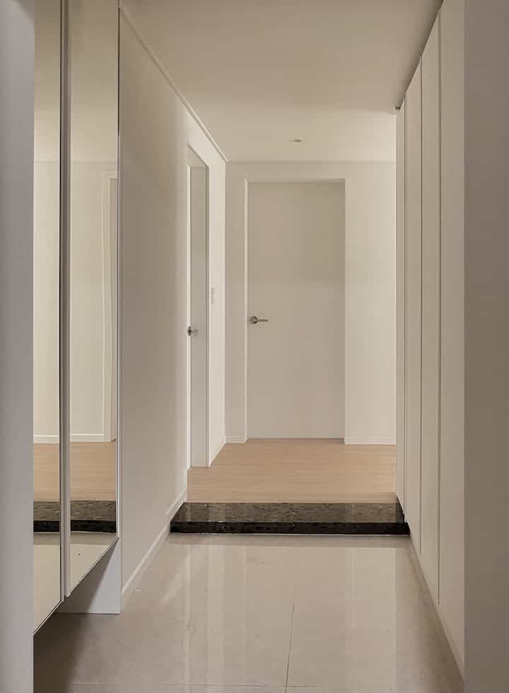 Modern entrance space in white tones featuring a clean shoe cabinet and Domus handle, creating a cozy atmosphere