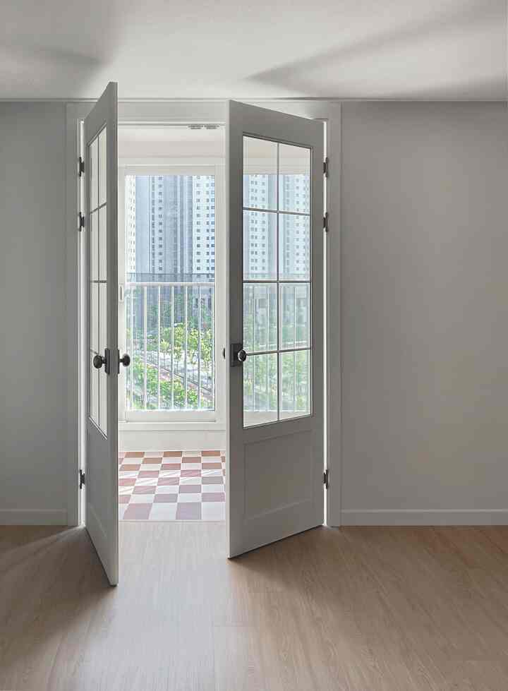 White and wood tonal interior with balcony visible through interior doors, creating a clean and natural atmosphere