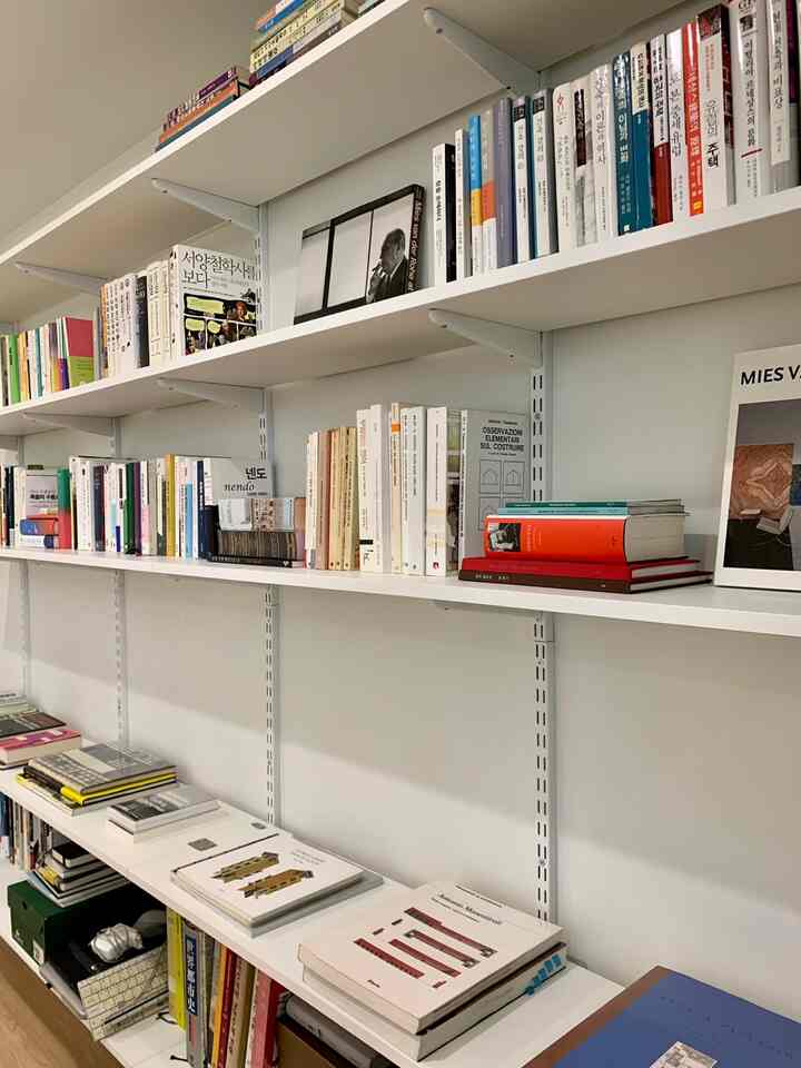 White-toned study space with clean wall-mounted shelves filled with assorted books, showcasing a modern look