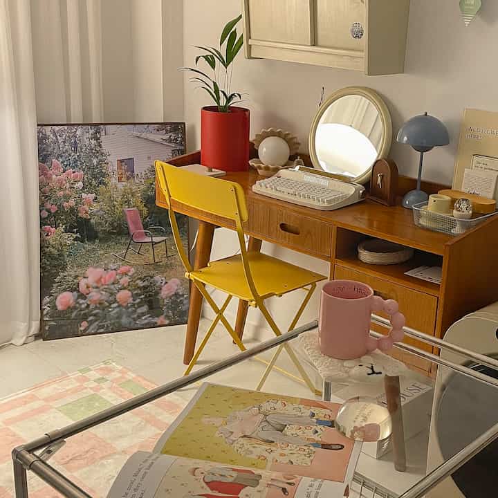 木目調と黄色、赤が調和した小さなホームオフィス空間、机と黄色い椅子、ピンクのマグが温かみのある雰囲気を醸し出すインテリア