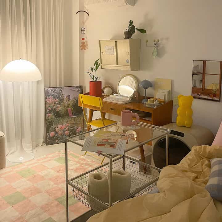 Cozy bedroom in warm beige and yellow tones featuring vintage style desk and lighting, with a pastel checkered rug, creating a welcoming atmosphere
