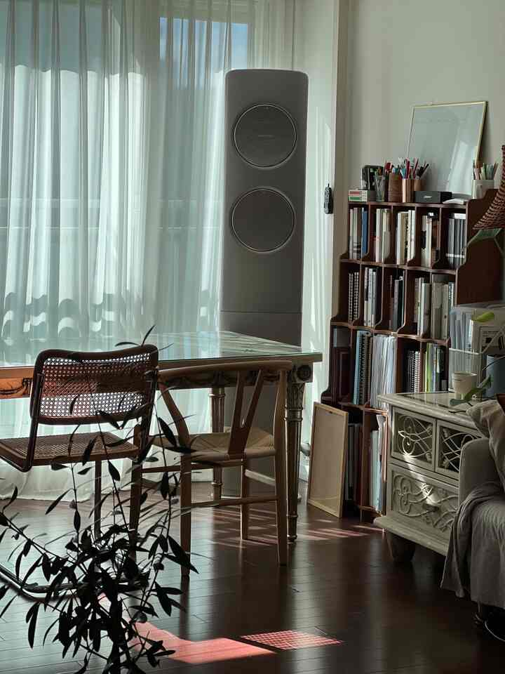 White and brown toned balcony-adjacent dining room featuring rattan chairs and a bookshelf in a natural, cozy home office space