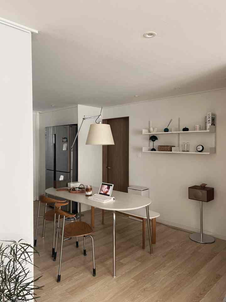 Modern kitchen with white and wood tones, featuring a dining table and chairs as central elements creating a clean and bright atmosphere