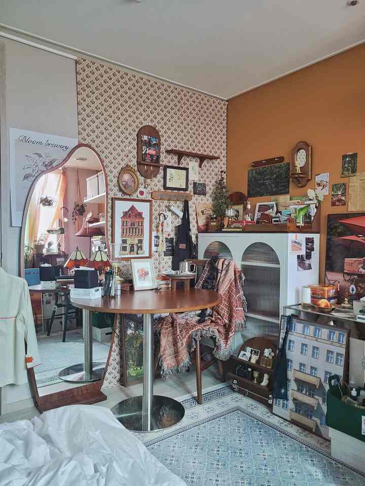 Cozy small study featuring warm wood tones and vintage decor with layered wall art and furniture