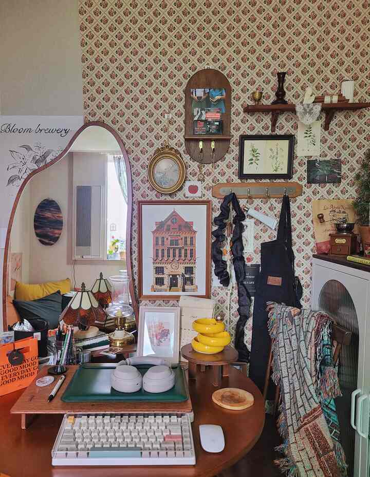 Wood tone vintage study featuring shelves and various framed art creating a cozy workspace