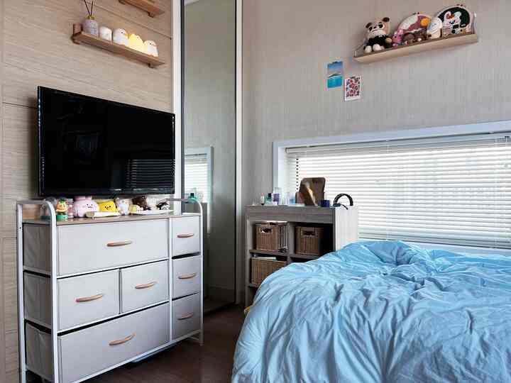 Beige-toned bedroom featuring sky blue bedding, a built-in closet with mirror, and organized storage cabinets for a tidy feel