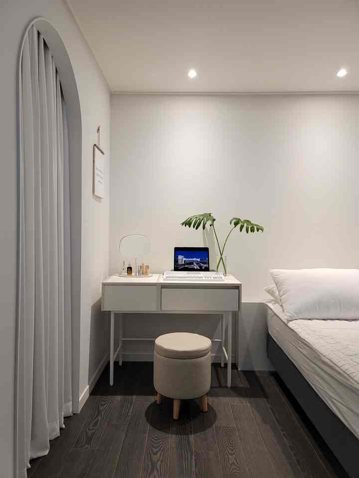 White and dark brown toned bedroom featuring a simple desk and stool in a natural modern style