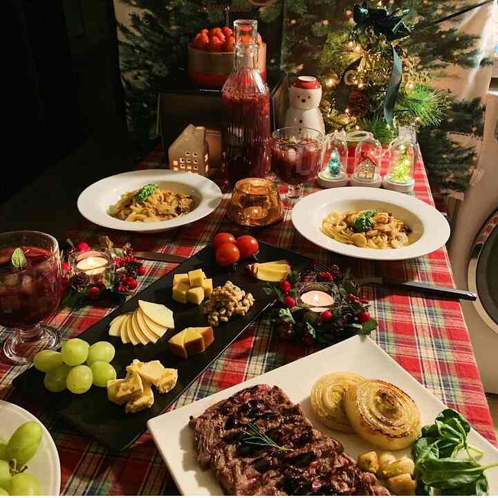 A home party table setting on a red plaid tablecloth featuring a Christmas tree and candles