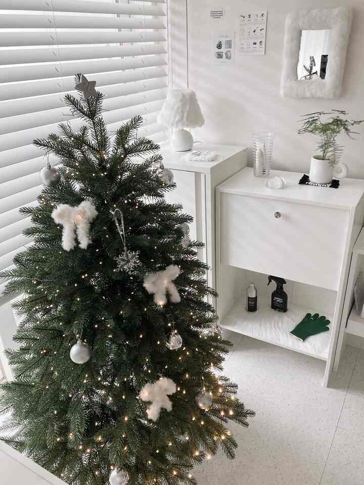 White-toned living room featuring wood blinds and a decorated Christmas tree with a clean, natural modern style