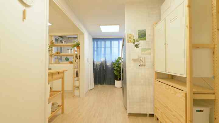 White and wood tone narrow kitchen space featuring relocated refrigerator and clean molding, enhancing openness
