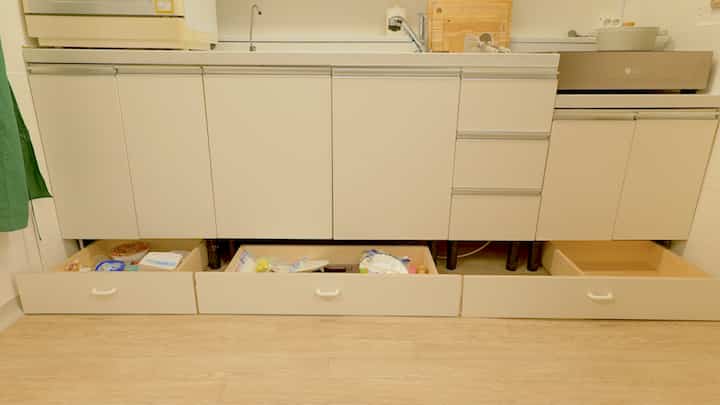 Beige-toned kitchen lower cabinets featuring custom gap storage drawers under the sink in a practical setting
