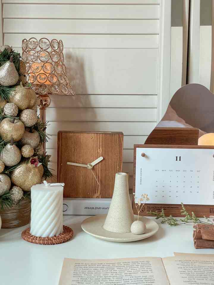 Cozy home office desk space with white walls, wood tone decor including candle and ceramic incense holder