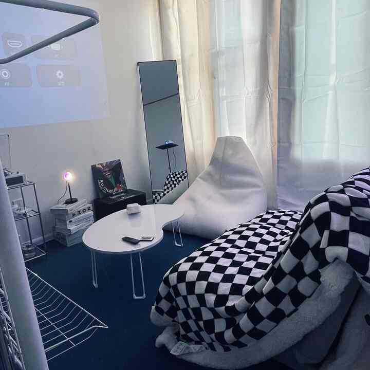 ホワイトとネイビートーンのワンルームリビング、ビーズクッションとチェッカーボード柄のブランケットが配置されたミッドセンチュリーモダンの空間