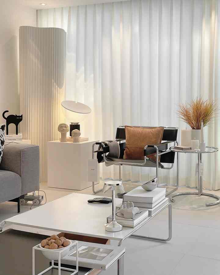 Modern living room with white curtains and silver frame furniture, featuring a leather cushion armchair and a white coffee table