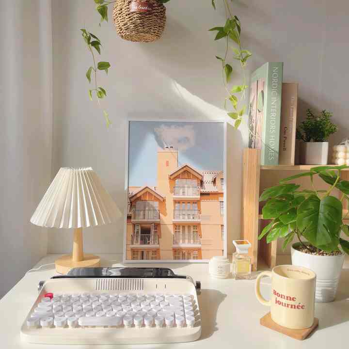 White and wood tone home office space with plants and decor, featuring a simple and cozy desk setup