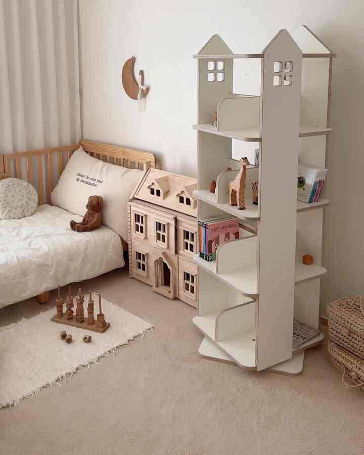 ベージュとホワイトの色調の子供部屋、ベビーベッドと木製のおもちゃ収納棚、本棚が配置された温かみのあるインテリア