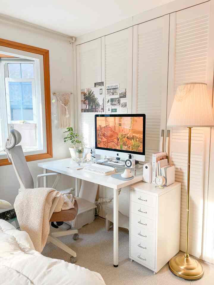 Natural and white toned compact home office featuring a desk, office chair, and gold floor lamp creating a warm atmosphere.