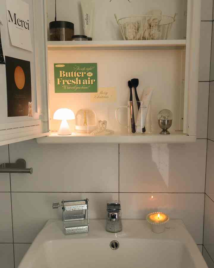 Warmly lit bathroom sink area in beige and white tones featuring storage shelves and decorative lighting