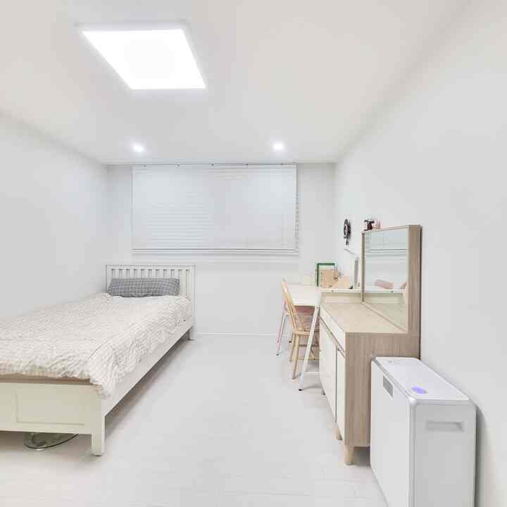 Bright, tidy kids' room in white and natural tones featuring a single bed, desk, and wooden furniture
