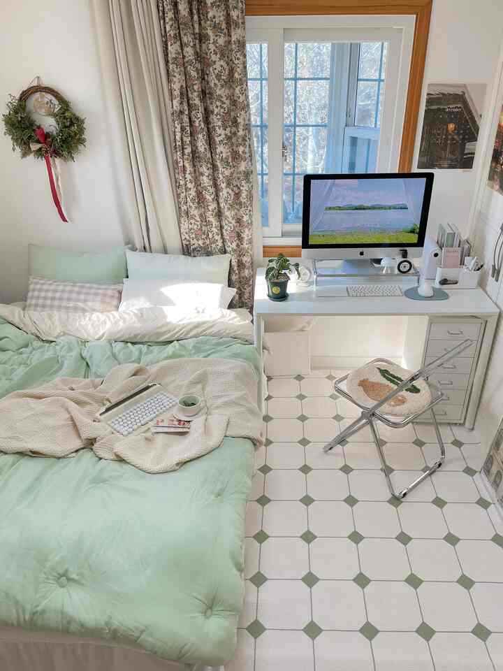 White and light green toned bedroom and home office featuring modal bedding and transparent chair in a cozy modern setting