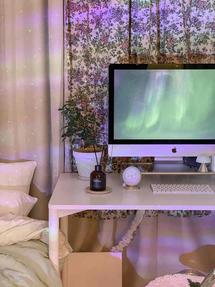 White-toned home office space featuring computer desk with diffuser, clock, and plant creating cozy atmosphere