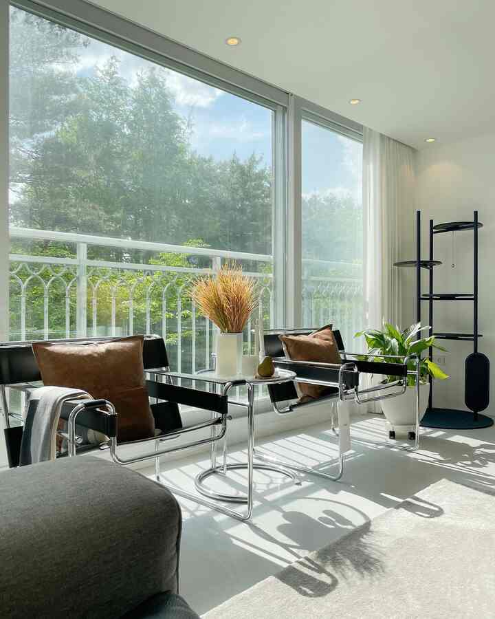 Bright white-toned living room featuring two mid-century modern armchairs, a cat tower, and brown cushions in a calm atmosphere