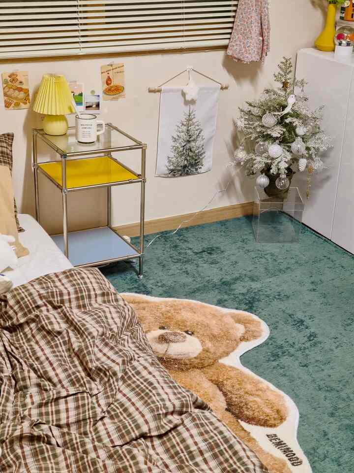 Cozy corner bedroom with white and brown tones, featuring a bear-shaped rug and mini Christmas tree decor