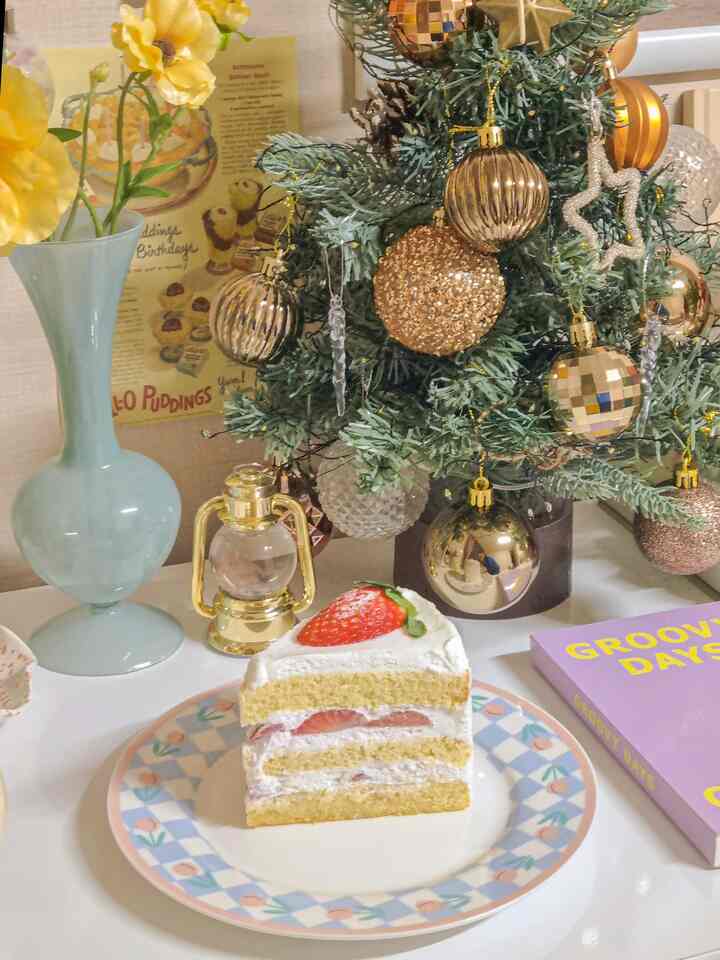 Cozy cafe-style small table featuring a decorated Christmas mini tree and strawberry cake, creating a warm ambiance
