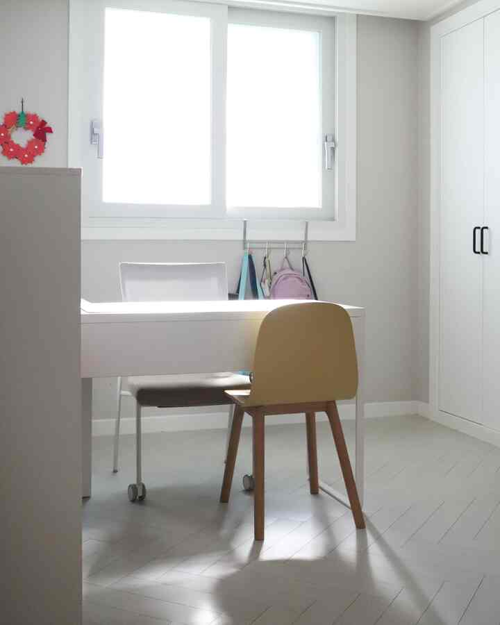 Bright white and wood-tone compact kids' study room with a clean desk and chairs arranged neatly