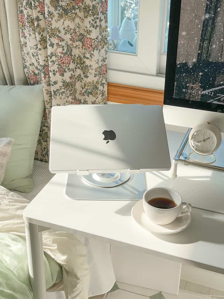 ホワイトと淡いグリーンの色調のホームオフィス、ノートパソコンスタンドとシンプルなデスクが配置された雰囲気のあるインテリア