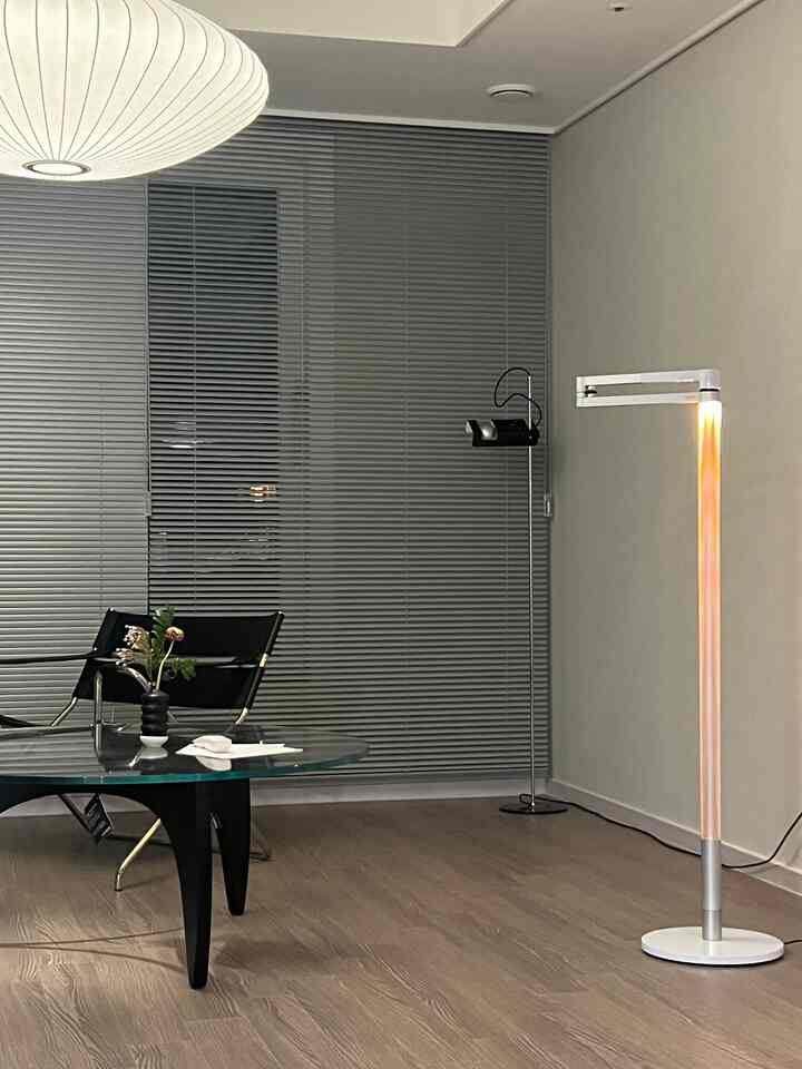 Gray-toned study space featuring wood-tone flooring, black furniture, and a Dyson floor lamp creating a modern atmosphere